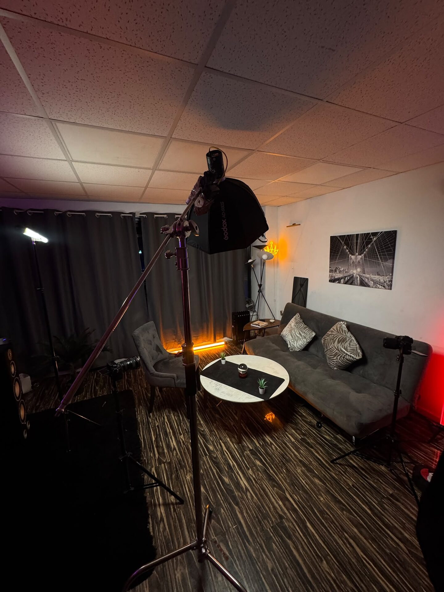 Lounge set with a grey sofa, round marble table and a warm orange tube light under a softbox