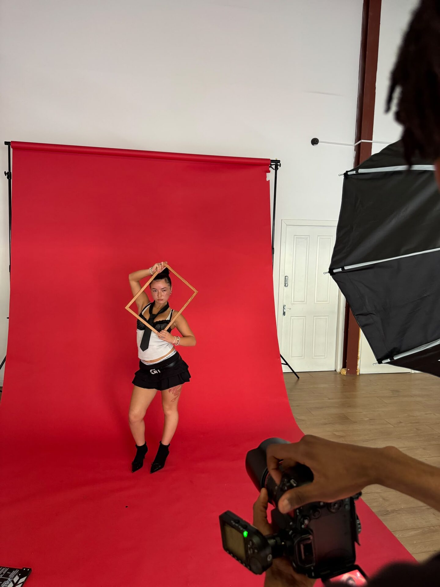 Photographer shooting a model holding a wooden frame on the red backdrop