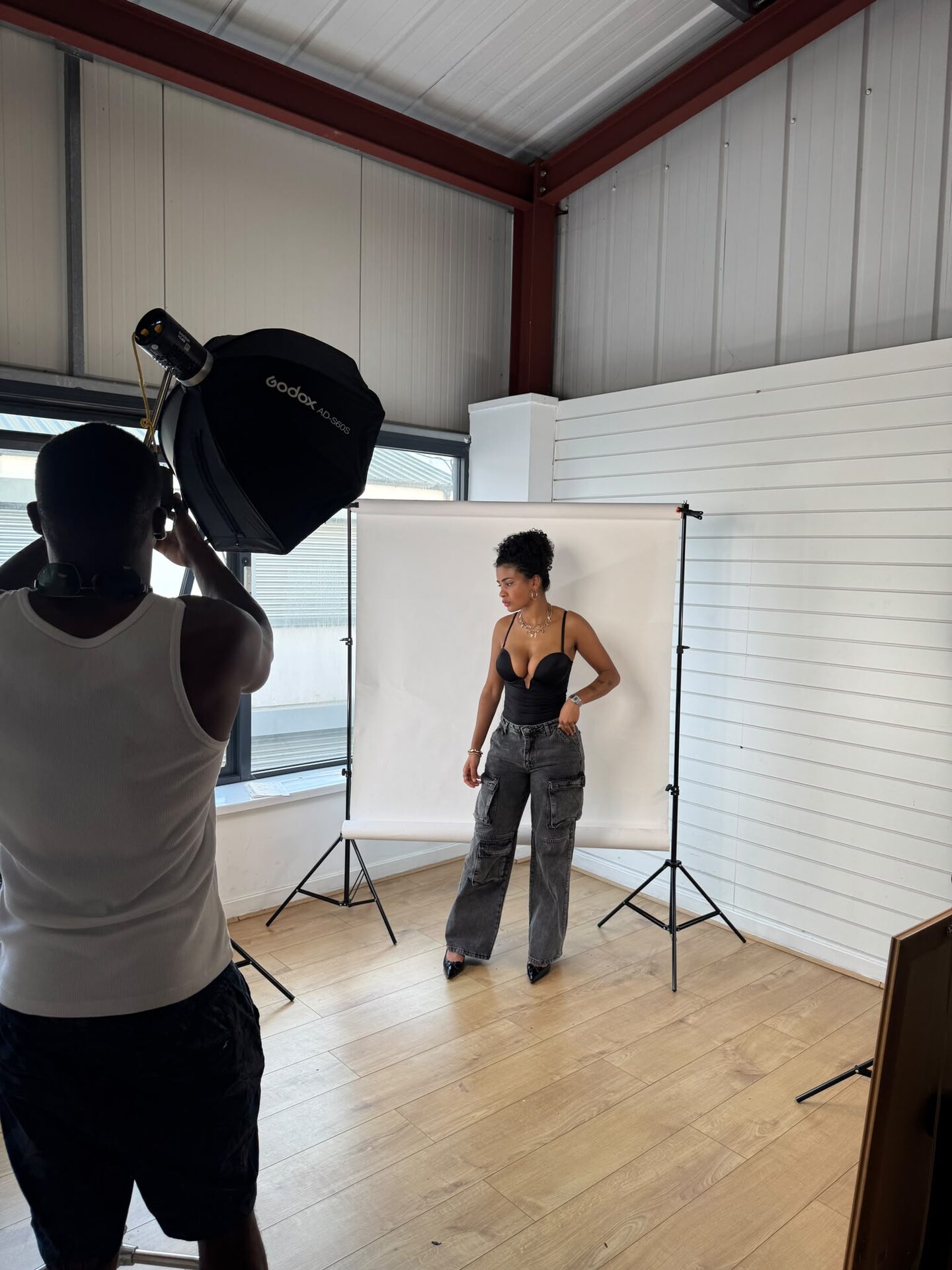 Photographer with a softbox shooting a model in front of the white backdrop