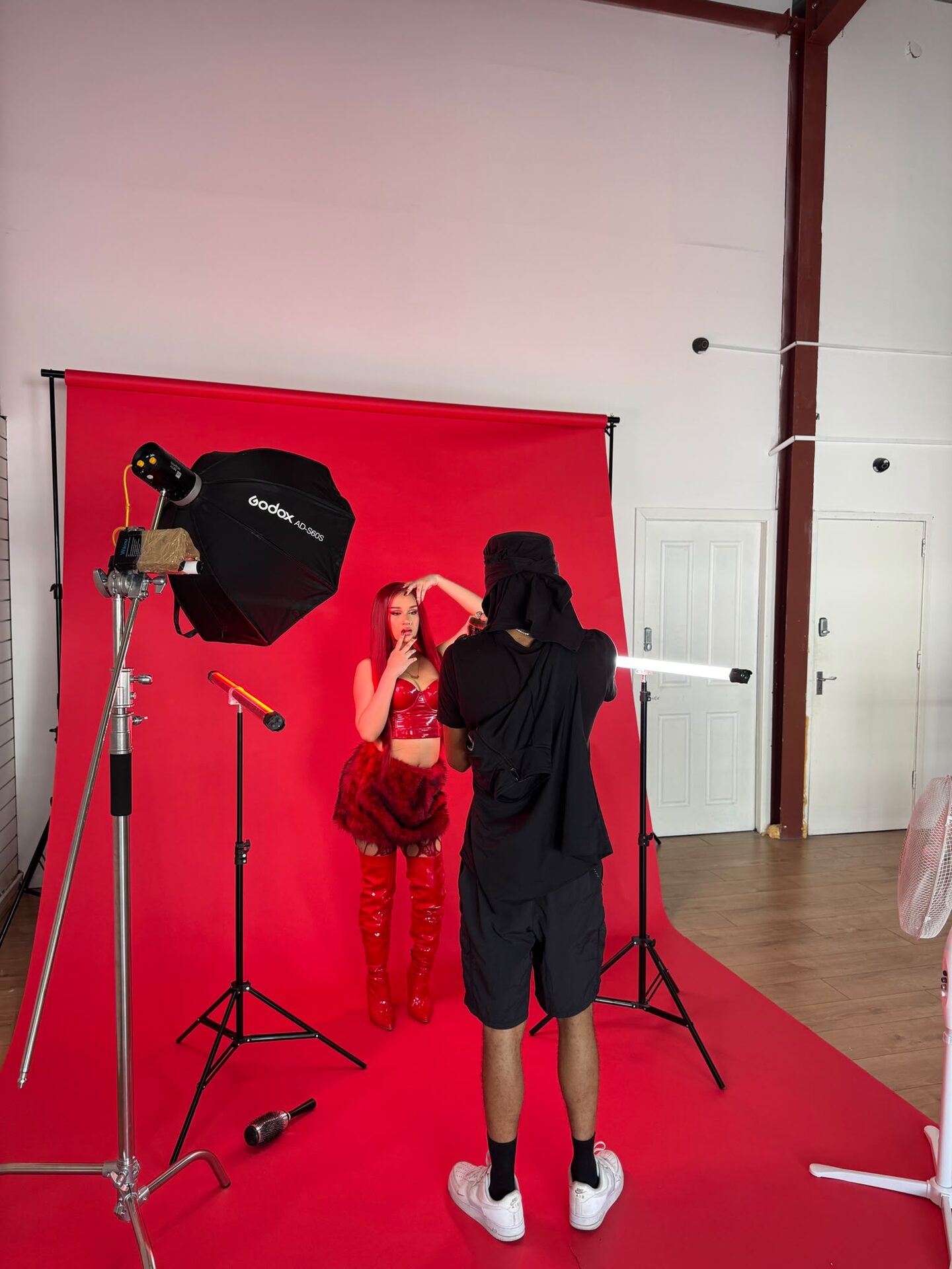 Model in red on the red backdrop with red and white tube lights and a photographer working